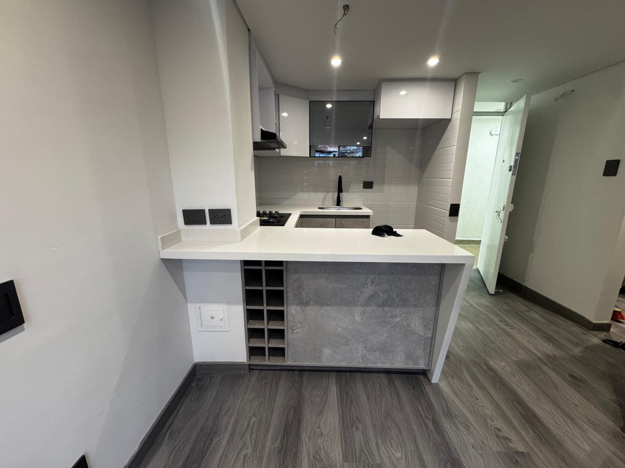 Cocina integral con mesón blanco y vinoteca